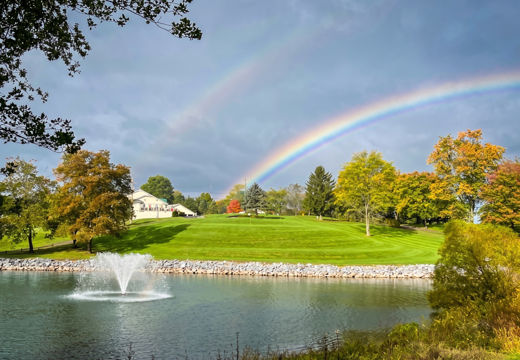 Valley Green Golf Course fairway with pond, fountain, and rainbow
